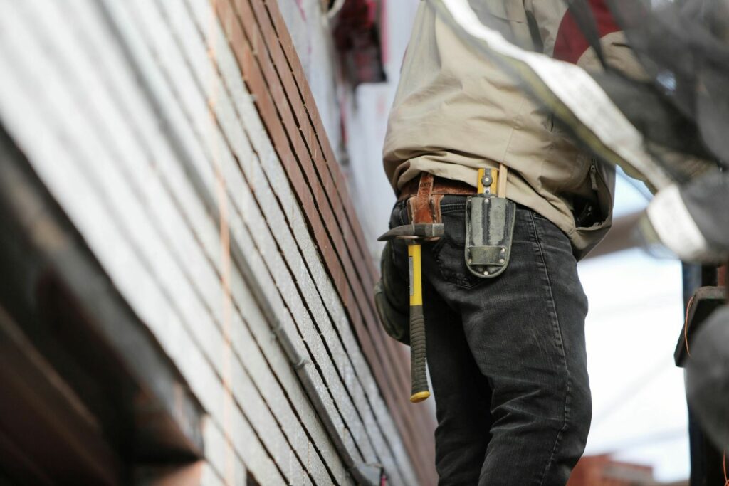 Construction worker with tool belt beside a wall with insulation material during retrofitting process