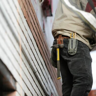 Construction worker with tool belt beside a wall with insulation material during retrofitting process